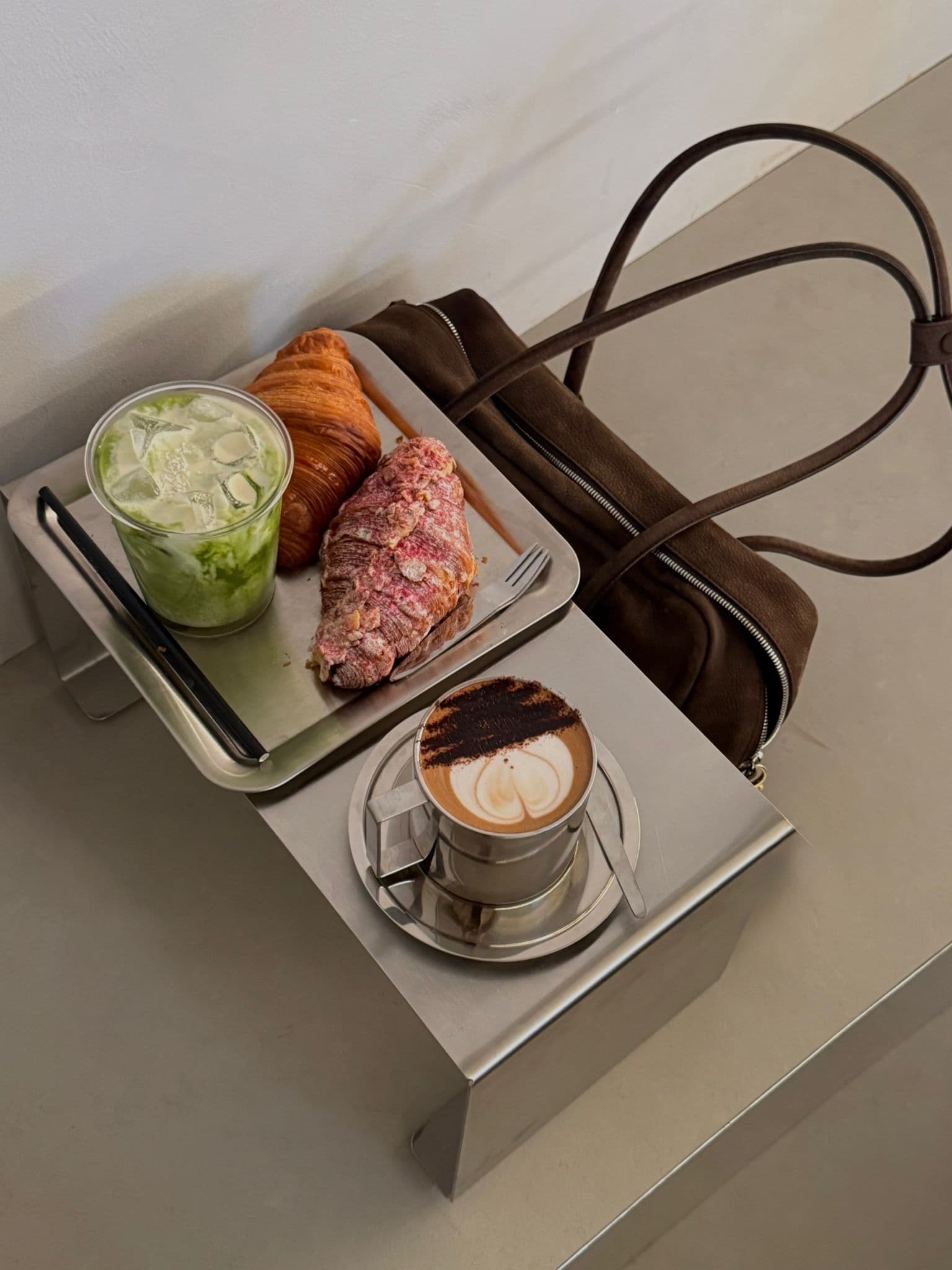 A cafe table with pastries, matcha and coffee