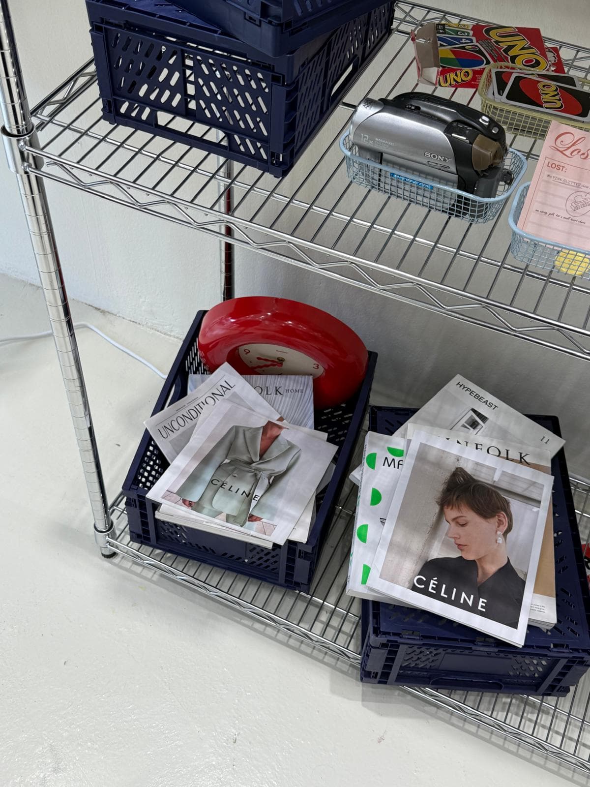 A shelf with magazines, a video camera and card games